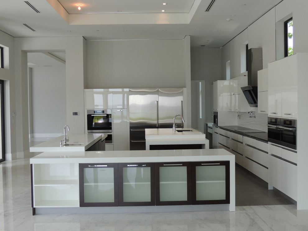 Große Moderne Wohnküche in U-Form mit Doppelwaschbecken, flächenbündigen Schrankfronten, weißen Schränken, Quarzit-Arbeitsplatte, Küchenrückwand in Weiß, Rückwand aus Glasfliesen, Küchengeräten aus Edelstahl, Marmorboden und zwei Kücheninseln in Miami
