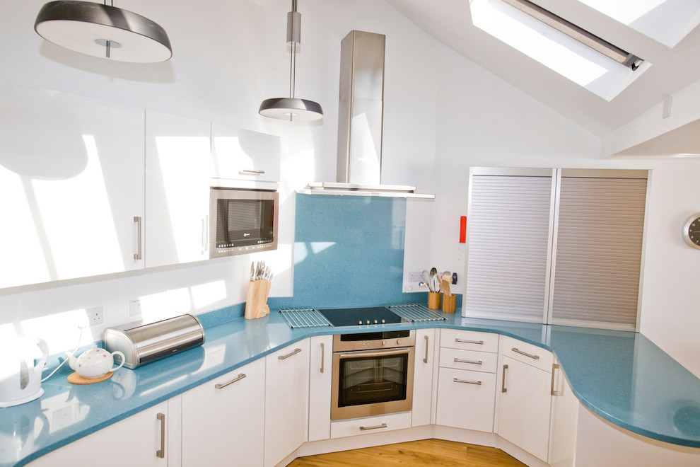 Coastal u-shaped kitchen/diner in Cornwall with a submerged sink, flat-panel cabinets, white cabinets, quartz worktops, blue splashback, stone slab splashback and stainless steel appliances.