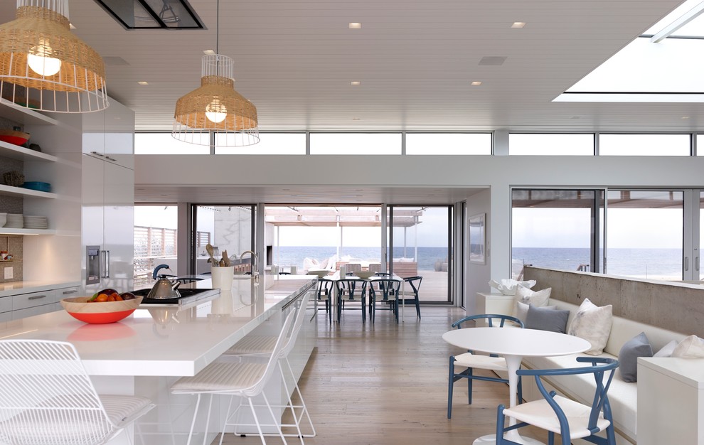 Zweizeilige Moderne Küche mit flächenbündigen Schrankfronten, weißen Schränken, hellem Holzboden und Kücheninsel in New York