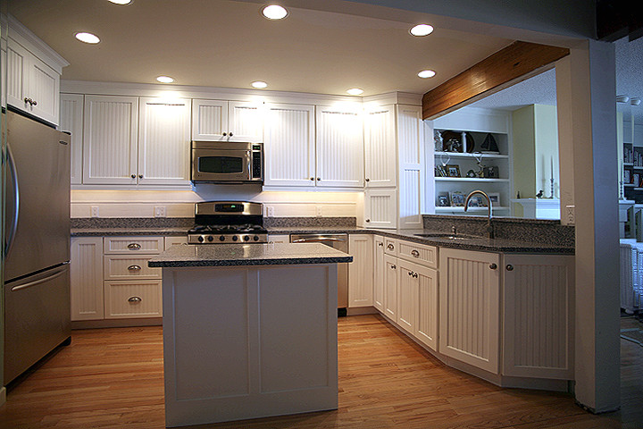 Idéer för ett modernt kök, med en undermonterad diskho, skåp i shakerstil, vita skåp, bänkskiva i kvarts, vitt stänkskydd, stänkskydd i keramik, rostfria vitvaror, mellanmörkt trägolv och en köksö