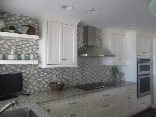 Photo of a medium sized beach style u-shaped kitchen in Providence with a submerged sink, shaker cabinets, white cabinets, granite worktops, grey splashback, glass tiled splashback, stainless steel appliances, dark hardwood flooring, a breakfast bar and brown floors.