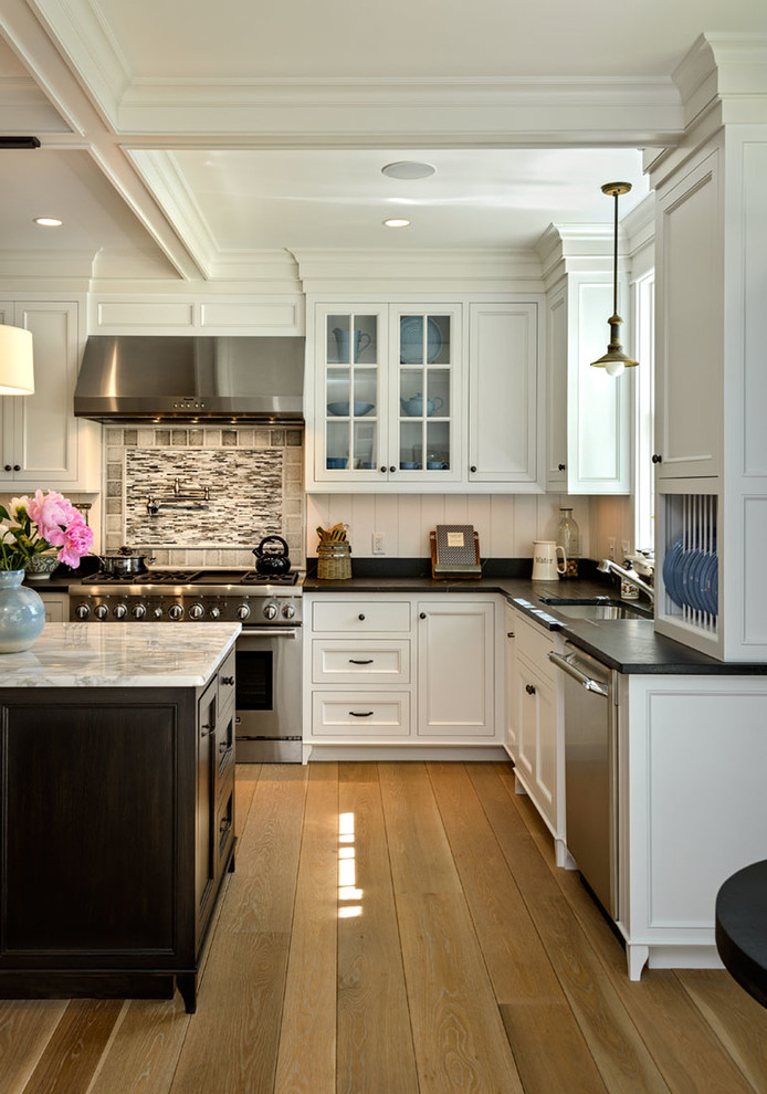 Open concept kitchen - mid-sized coastal l-shaped light wood floor and beige floor open concept kitchen idea in Boston with an undermount sink, recessed-panel cabinets, white cabinets, solid surface countertops, white backsplash, wood backsplash, stainless steel appliances and an island