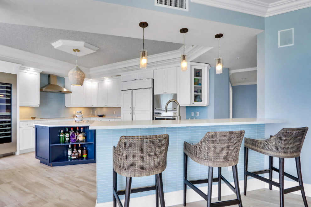 Inspiration for a mid-sized coastal u-shaped porcelain tile and beige floor kitchen pantry remodel in Other with a double-bowl sink, raised-panel cabinets, white cabinets, quartz countertops, blue backsplash, glass tile backsplash, stainless steel appliances, an island and white countertops