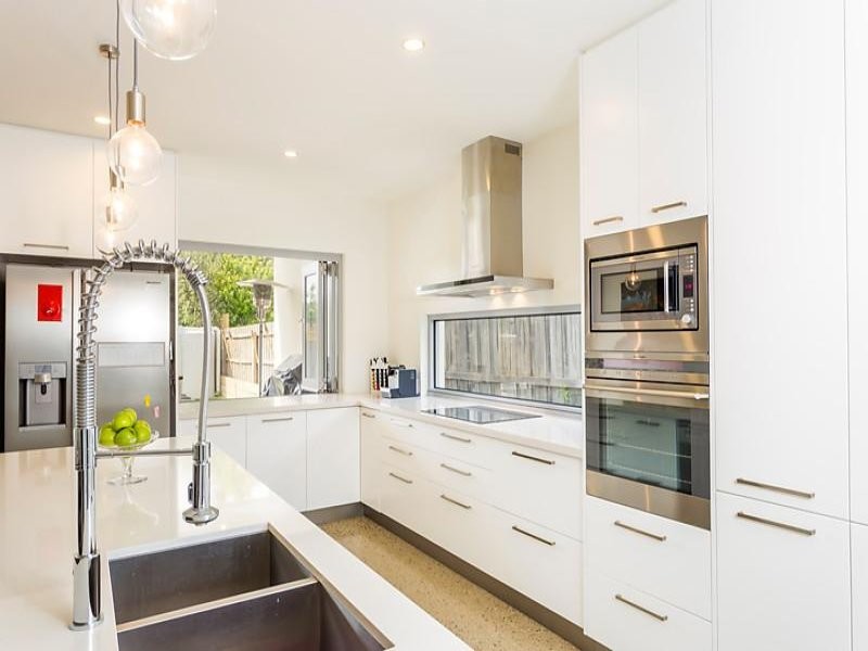 This is an example of a large contemporary l-shaped open plan kitchen in Geelong with a submerged sink, flat-panel cabinets, white cabinets, terrazzo worktops, stainless steel appliances, concrete flooring and an island.