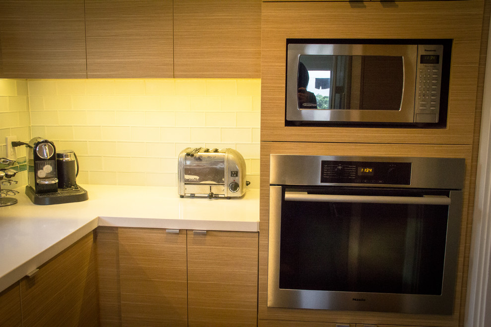 Immagine di una cucina minimal con lavello sottopiano, ante lisce, ante in legno chiaro, top in quarzite, paraspruzzi bianco, paraspruzzi con piastrelle di vetro e elettrodomestici in acciaio inossidabile