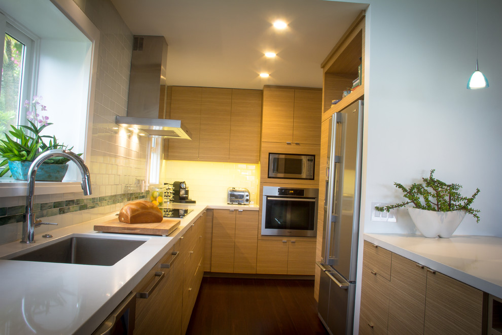 Contemporary galley kitchen/diner in Hawaii with a submerged sink, flat-panel cabinets, light wood cabinets, quartz worktops, white splashback, glass tiled splashback and stainless steel appliances.