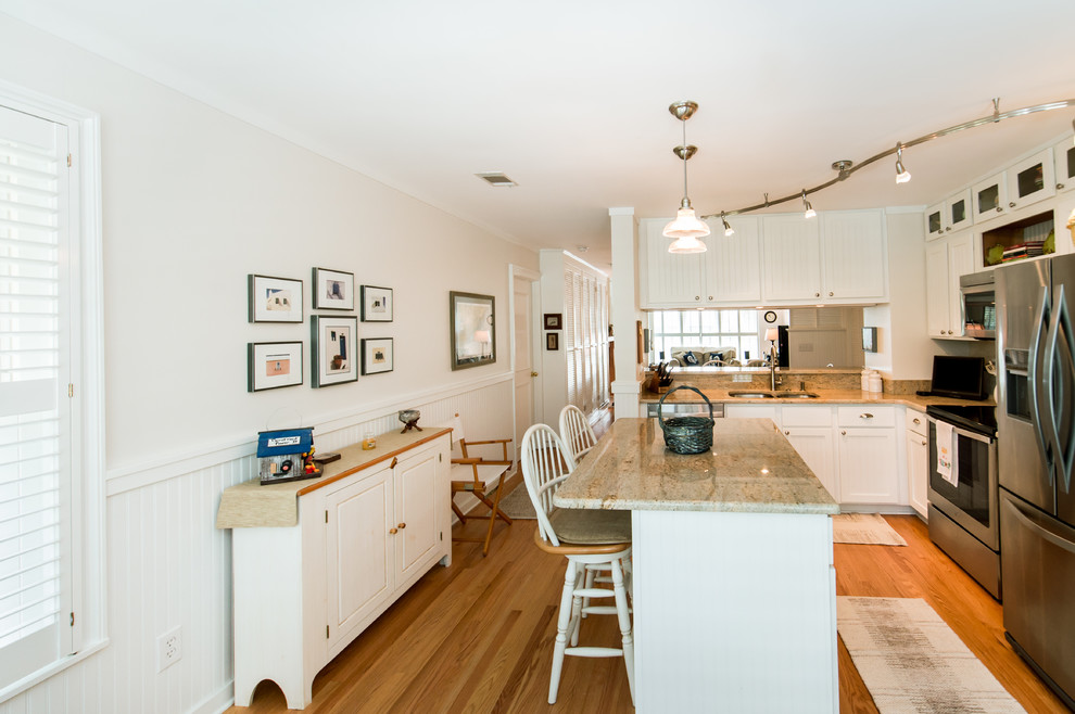Large beach style l-shaped medium tone wood floor eat-in kitchen photo in Charleston with an undermount sink, louvered cabinets, white cabinets, granite countertops, beige backsplash, stone tile backsplash, stainless steel appliances and an island