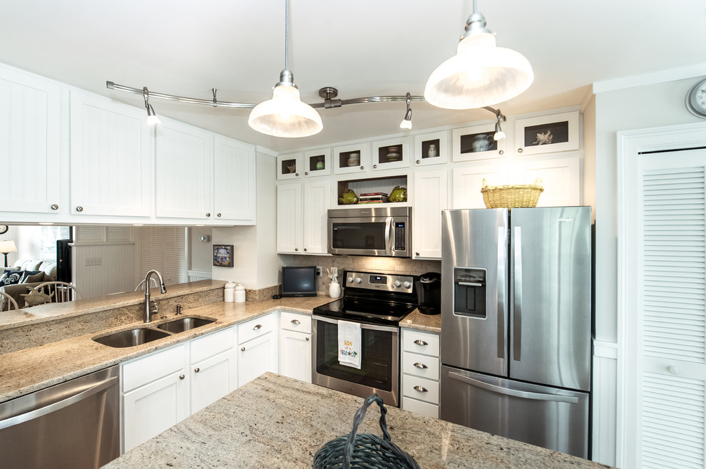 Eat-in kitchen - large coastal l-shaped medium tone wood floor eat-in kitchen idea in Charleston with an undermount sink, louvered cabinets, white cabinets, granite countertops, beige backsplash, stone tile backsplash, stainless steel appliances and an island