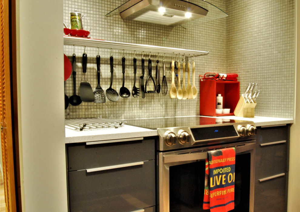 Ejemplo de cocina bohemia con salpicadero gris, salpicadero de vidrio templado, electrodomésticos de acero inoxidable y península