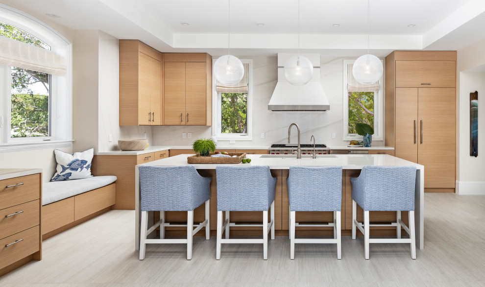Beach style l-shaped gray floor kitchen photo in Detroit with an undermount sink, flat-panel cabinets, medium tone wood cabinets, white backsplash, stone slab backsplash, stainless steel appliances, an island and white countertops