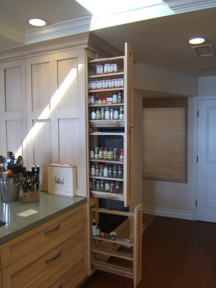 Cette image montre une cuisine ouverte parallèle design en bois clair de taille moyenne avec un placard à porte shaker, un plan de travail en quartz modifié et un sol en liège.