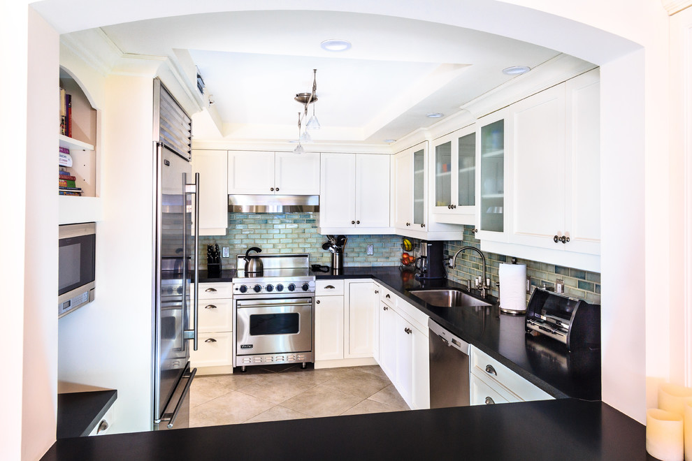 Enclosed kitchen - traditional u-shaped enclosed kitchen idea in Miami with an undermount sink, recessed-panel cabinets, granite countertops, green backsplash, subway tile backsplash, stainless steel appliances and white cabinets