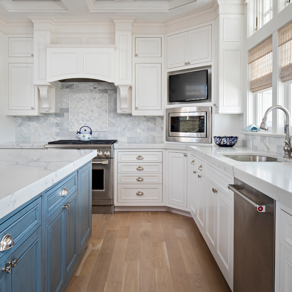 Exempel på ett mellanstort klassiskt kök, med en nedsänkt diskho, luckor med infälld panel, vita skåp, bänkskiva i kvarts, vitt stänkskydd, stänkskydd i marmor, rostfria vitvaror, ljust trägolv, en köksö och brunt golv