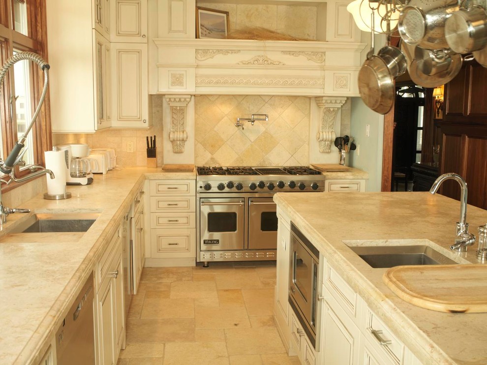 Exempel på ett avskilt, mellanstort medelhavsstil u-kök, med en undermonterad diskho, luckor med profilerade fronter, vita skåp, bänkskiva i kalksten, beige stänkskydd, stänkskydd i stenkakel, rostfria vitvaror, travertin golv och en köksö
