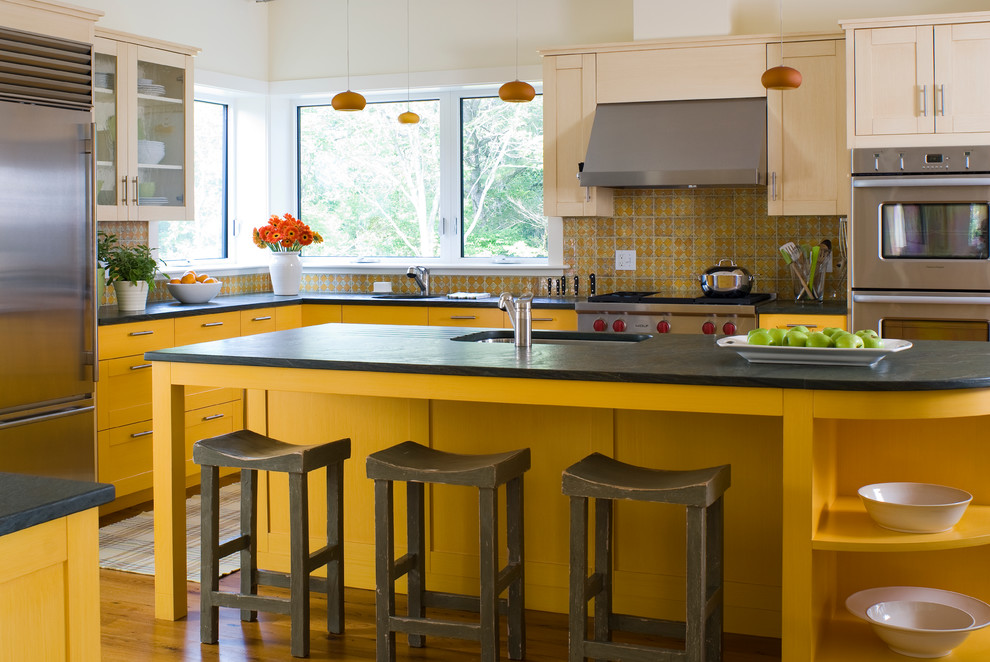 Klassische Küche mit Schrankfronten im Shaker-Stil, gelben Schränken, Küchenrückwand in Gelb, Küchengeräten aus Edelstahl, braunem Holzboden und Kücheninsel in Portland Maine
