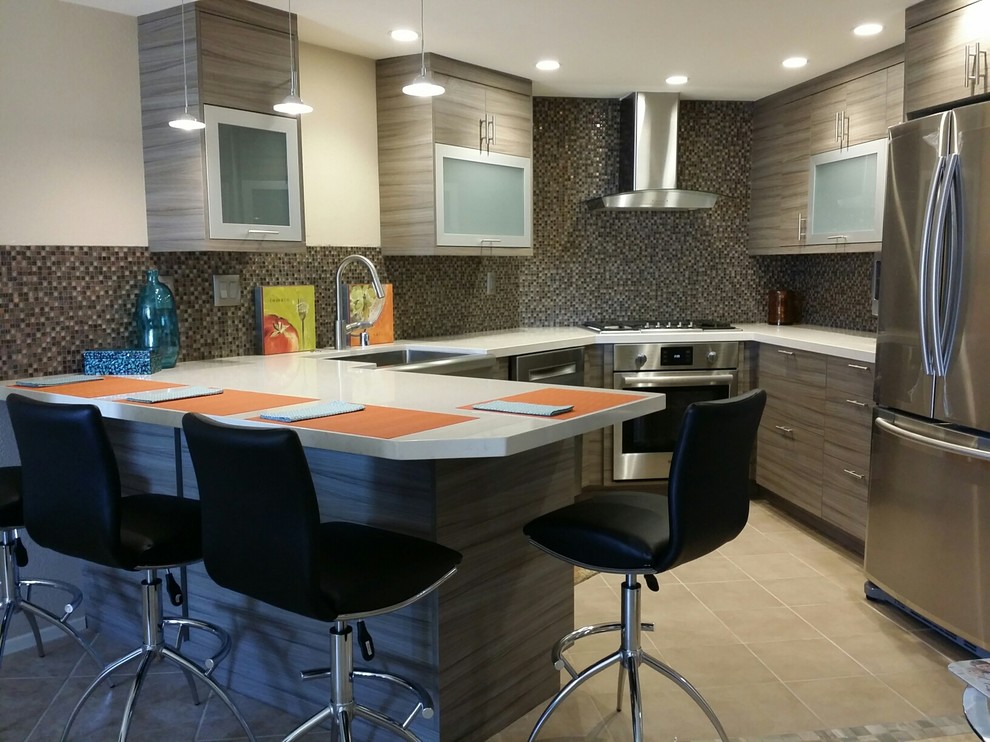Mid-sized beach style u-shaped ceramic tile eat-in kitchen photo in San Diego with an undermount sink, glass-front cabinets, gray cabinets, quartz countertops, gray backsplash, mosaic tile backsplash, stainless steel appliances and a peninsula