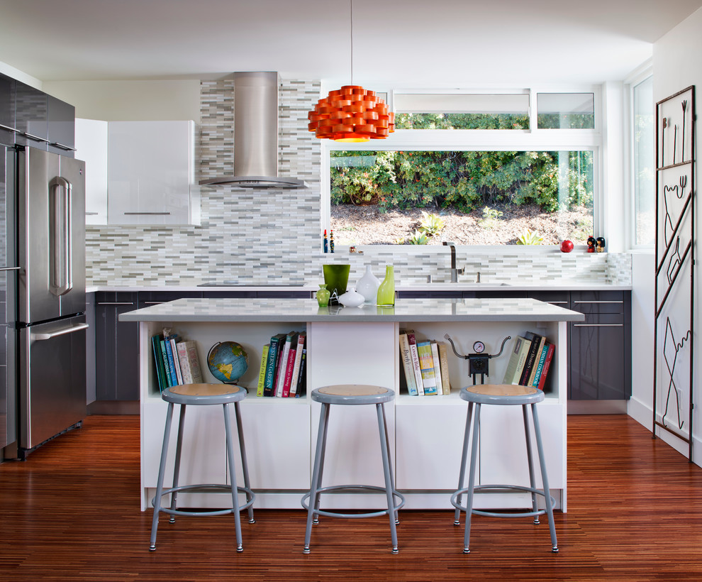 Moderne Küche mit flächenbündigen Schrankfronten, weißen Schränken, bunter Rückwand, Küchengeräten aus Edelstahl und Kücheninsel in Sonstige