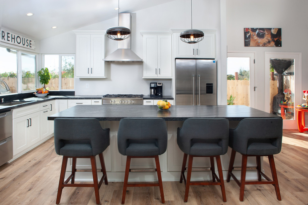 Foto di una cucina moderna di medie dimensioni con lavello sottopiano, ante in stile shaker, ante bianche, top in granito, elettrodomestici in acciaio inossidabile, parquet chiaro, pavimento beige e top nero