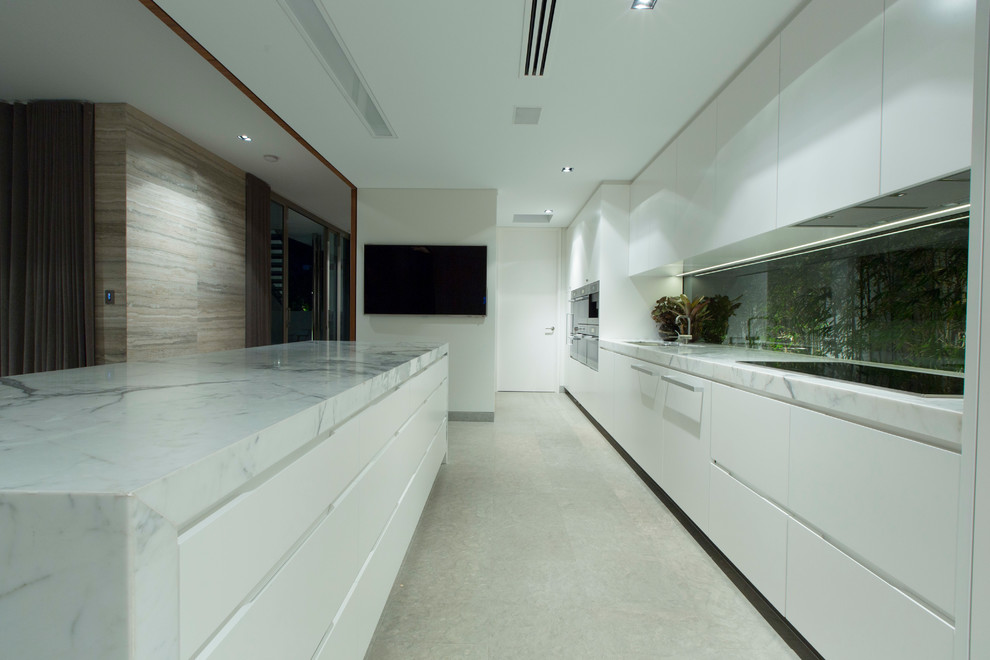 Cette image montre une cuisine parallèle design avec un évier encastré, une crédence en feuille de verre, un électroménager en acier inoxydable et îlot.