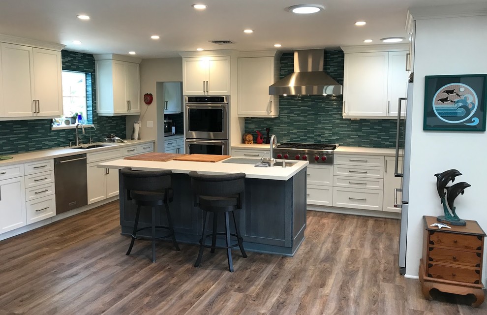 Inspiration for a mid-sized transitional u-shaped medium tone wood floor kitchen remodel in San Diego with an undermount sink, shaker cabinets, white cabinets, quartz countertops, blue backsplash, glass tile backsplash, stainless steel appliances, an island and white countertops