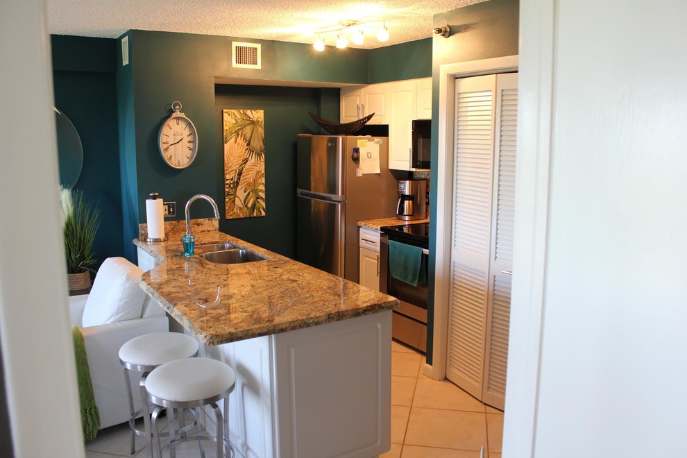 Open concept kitchen - small tropical single-wall ceramic tile and beige floor open concept kitchen idea in Boston with an undermount sink, raised-panel cabinets, white cabinets, granite countertops, brown backsplash, stone slab backsplash, stainless steel appliances, a peninsula and brown countertops