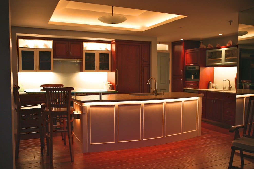 Mid-sized trendy l-shaped dark wood floor kitchen photo in Other with an undermount sink, recessed-panel cabinets, dark wood cabinets, limestone countertops, green backsplash, glass sheet backsplash, paneled appliances and an island