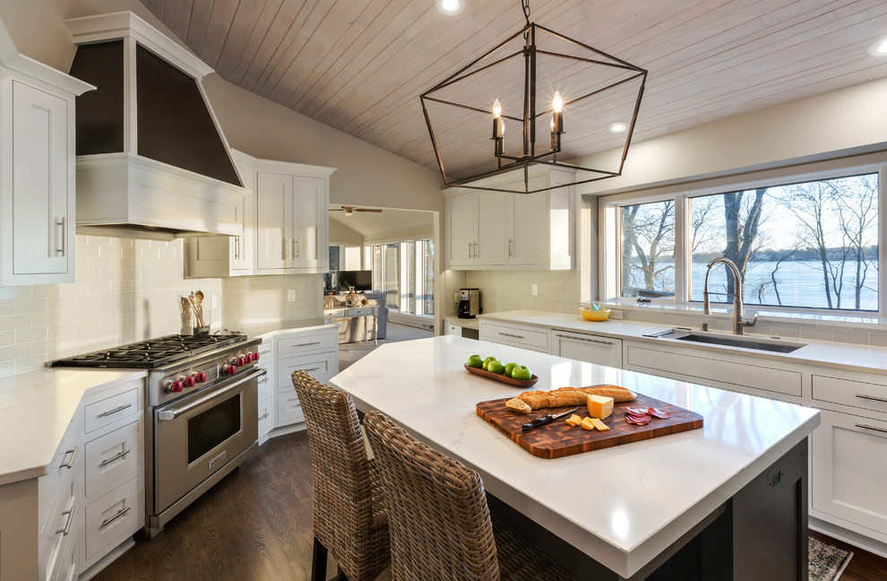 Large beach style u-shaped dark wood floor and brown floor enclosed kitchen photo in Milwaukee with an undermount sink, flat-panel cabinets, white cabinets, quartz countertops, gray backsplash, porcelain backsplash, stainless steel appliances, an island and white countertops