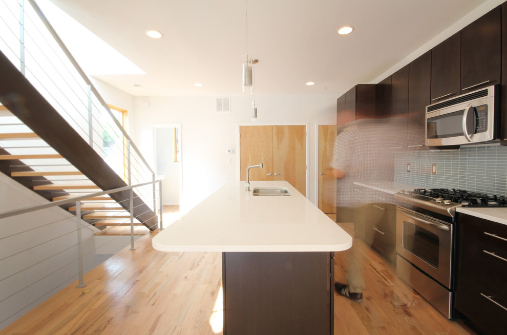 Immagine di una cucina contemporanea con lavello a doppia vasca, ante lisce, ante in legno bruno, paraspruzzi grigio e elettrodomestici in acciaio inossidabile