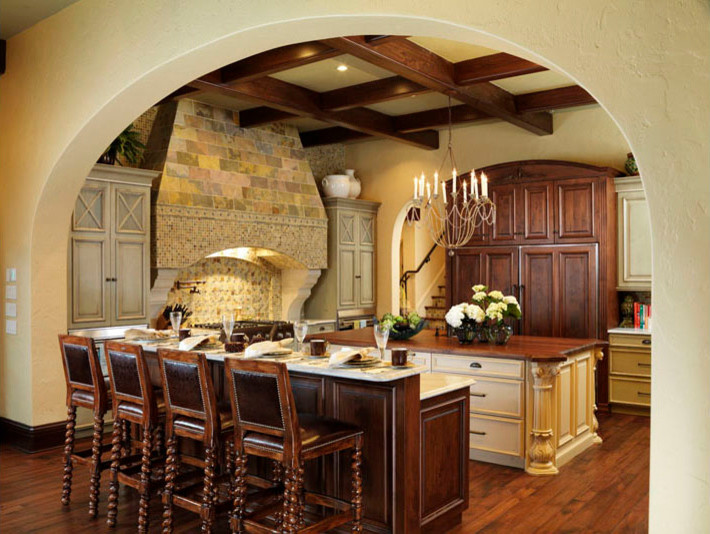 Inspiration for a mediterranean eat-in kitchen remodel in Tampa with raised-panel cabinets, distressed cabinets, granite countertops, multicolored backsplash and paneled appliances