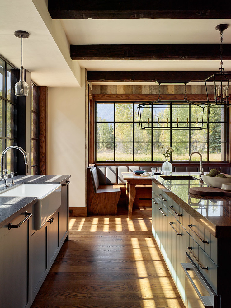 Urige Wohnküche mit Landhausspüle, flächenbündigen Schrankfronten, grünen Schränken und braunem Holzboden in Sonstige