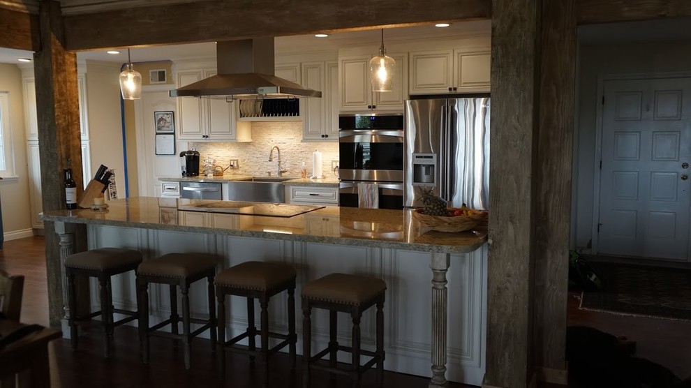 Exempel på ett stort klassiskt kök, med en rustik diskho, luckor med upphöjd panel, gula skåp, granitbänkskiva, beige stänkskydd, stänkskydd i keramik, rostfria vitvaror och ljust trägolv