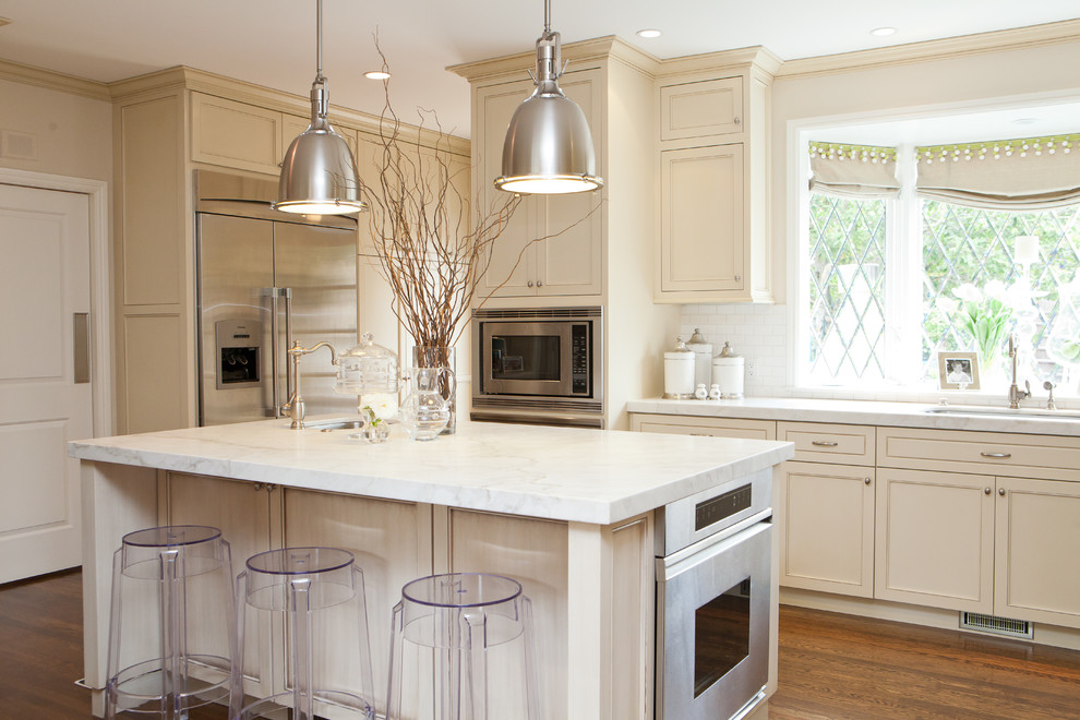 Exempel på ett klassiskt kök, med luckor med infälld panel, beige skåp, marmorbänkskiva, vitt stänkskydd och rostfria vitvaror