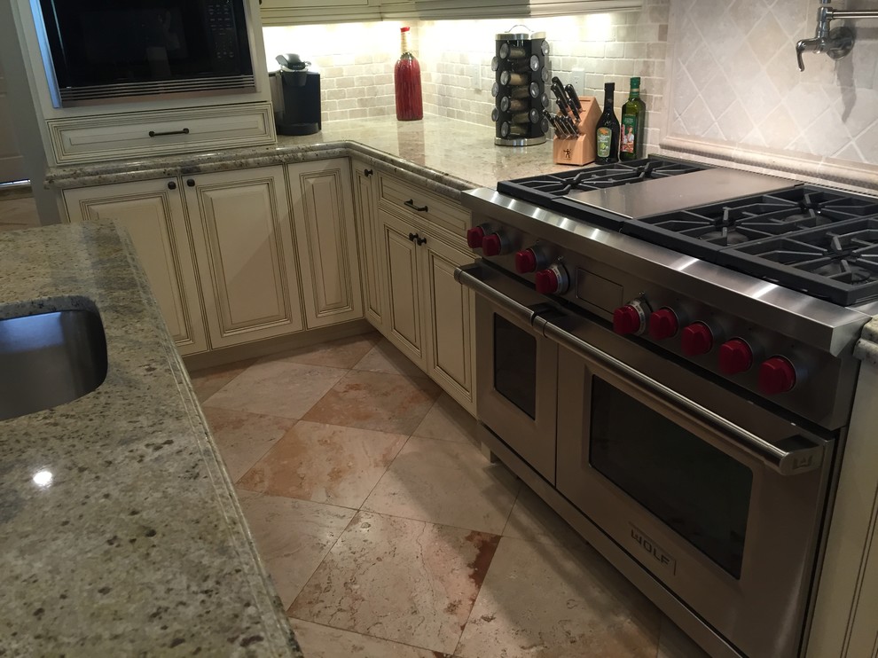 Exempel på ett mellanstort modernt linjärt kök, med en enkel diskho, luckor med upphöjd panel, vita skåp, granitbänkskiva, beige stänkskydd, stänkskydd i stenkakel, rostfria vitvaror och en köksö