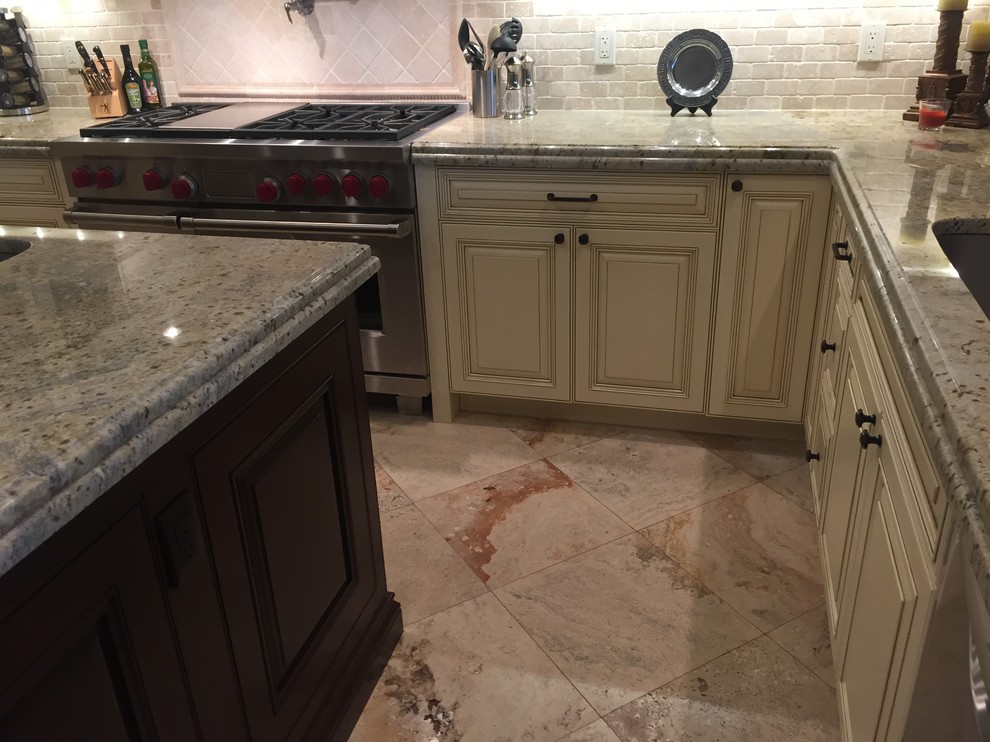 Bild på ett mellanstort funkis u-kök, med en enkel diskho, luckor med upphöjd panel, vita skåp, granitbänkskiva, beige stänkskydd, stänkskydd i stenkakel, rostfria vitvaror och en köksö