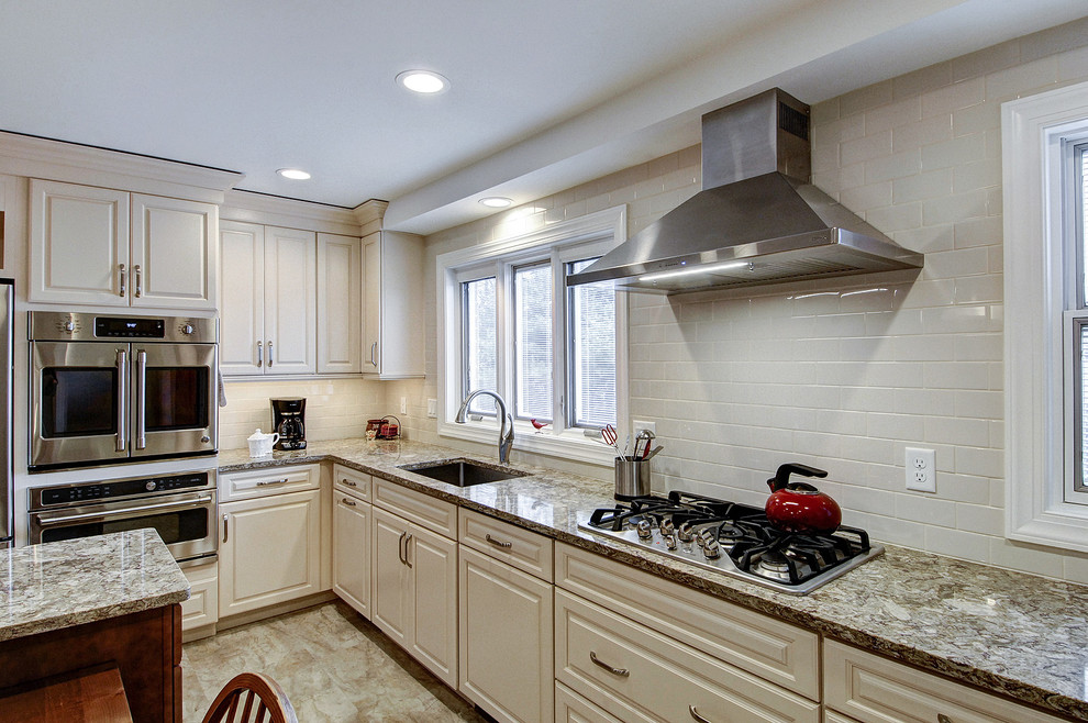 Exempel på ett mellanstort klassiskt grå grått kök, med en undermonterad diskho, luckor med upphöjd panel, vita skåp, granitbänkskiva, vitt stänkskydd, stänkskydd i keramik, rostfria vitvaror, vinylgolv, en köksö och brunt golv