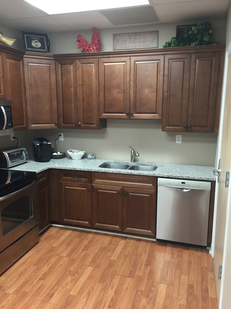 Klassisk inredning av ett litet kök, med en dubbel diskho, luckor med upphöjd panel, bruna skåp, bänkskiva i kvarts, beige stänkskydd, rostfria vitvaror och ljust trägolv