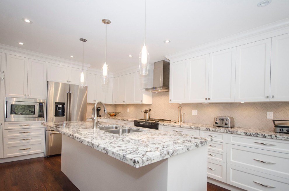 Large classic kitchen in Toronto with shaker cabinets, white cabinets, granite worktops, white splashback, medium hardwood flooring, an island and brown floors.