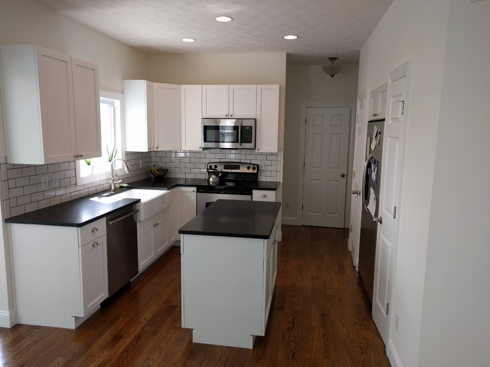 Open concept kitchen - small coastal l-shaped medium tone wood floor open concept kitchen idea in Cincinnati with a farmhouse sink, shaker cabinets, white cabinets, granite countertops, white backsplash, cement tile backsplash, stainless steel appliances and an island