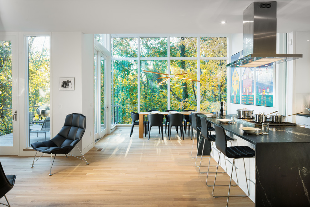 Moderne Wohnküche mit hellem Holzboden, flächenbündigen Schrankfronten, weißen Schränken, Küchengeräten aus Edelstahl, Kücheninsel und braunem Boden in Kolumbus