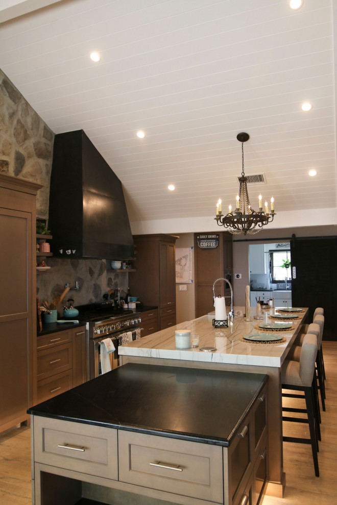 Idéer för ett mellanstort lantligt flerfärgad kök, med en rustik diskho, bruna skåp, svart stänkskydd, stänkskydd i stenkakel, rostfria vitvaror, mellanmörkt trägolv och en köksö