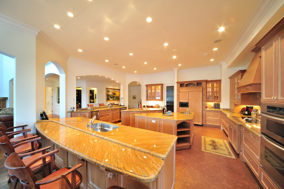Idéer för mycket stora medelhavsstil kök, med en undermonterad diskho, luckor med upphöjd panel, skåp i mellenmörkt trä, brunt stänkskydd, stänkskydd i sten, integrerade vitvaror, korkgolv, flera köksöar, marmorbänkskiva och brunt golv
