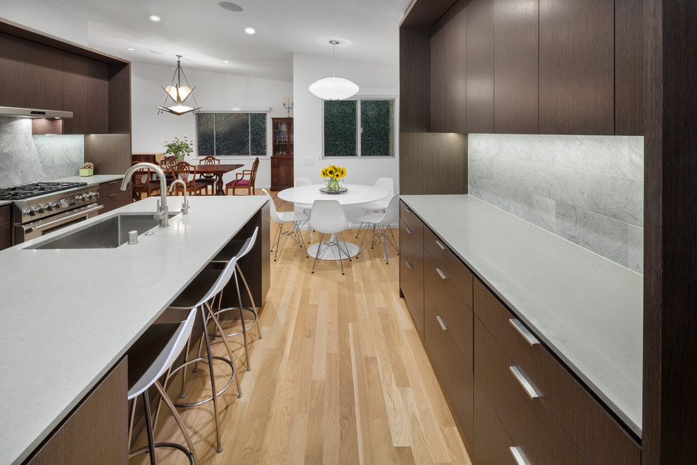 Große Moderne Küche in U-Form mit dunklen Holzschränken, Küchengeräten aus Edelstahl, hellem Holzboden und Kücheninsel in Los Angeles