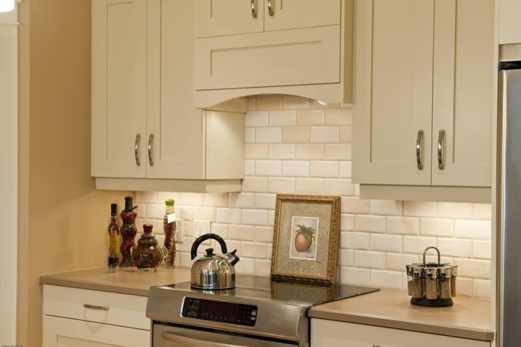Exempel på ett amerikanskt kök, med en undermonterad diskho, gula skåp, granitbänkskiva, vitt stänkskydd, stänkskydd i tunnelbanekakel, rostfria vitvaror, ljust trägolv och en köksö