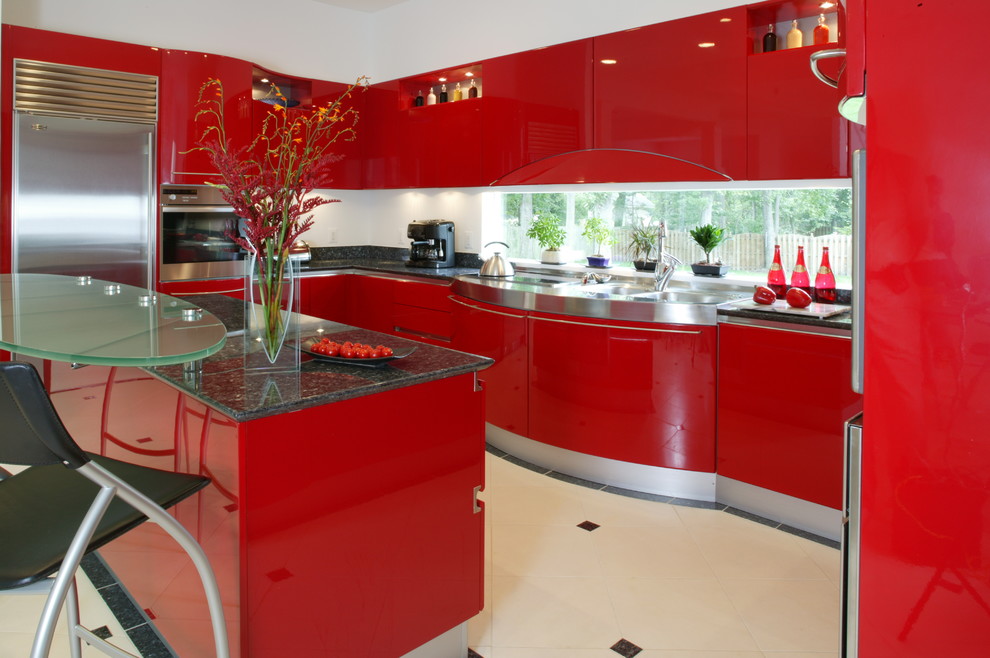На фото: п-образная кухня в стиле модернизм с плоскими фасадами, красными фасадами, белым фартуком, техникой из нержавеющей стали, островом и двойной мойкой