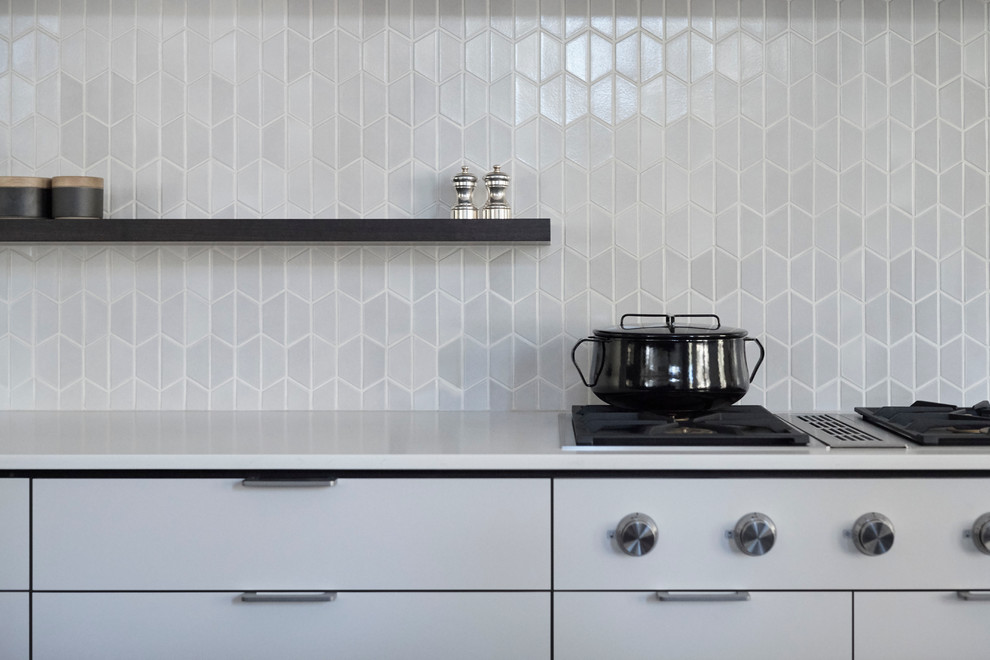 Inspiration for a large modern l-shaped porcelain tile open concept kitchen remodel in San Francisco with flat-panel cabinets, white cabinets, quartz countertops, white backsplash, ceramic backsplash, an island, an undermount sink and paneled appliances