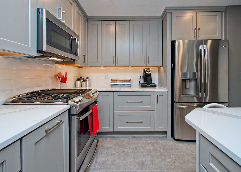 Mittelgroße Moderne Wohnküche in L-Form mit Unterbauwaschbecken, Schrankfronten im Shaker-Stil, grauen Schränken, Küchenrückwand in Weiß, Küchengeräten aus Edelstahl und Kücheninsel in Kansas City