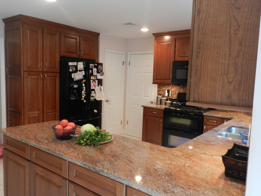 Foto på ett mellanstort vintage kök, med en dubbel diskho, luckor med upphöjd panel, skåp i mellenmörkt trä, granitbänkskiva, flerfärgad stänkskydd, svarta vitvaror, klinkergolv i porslin och en halv köksö
