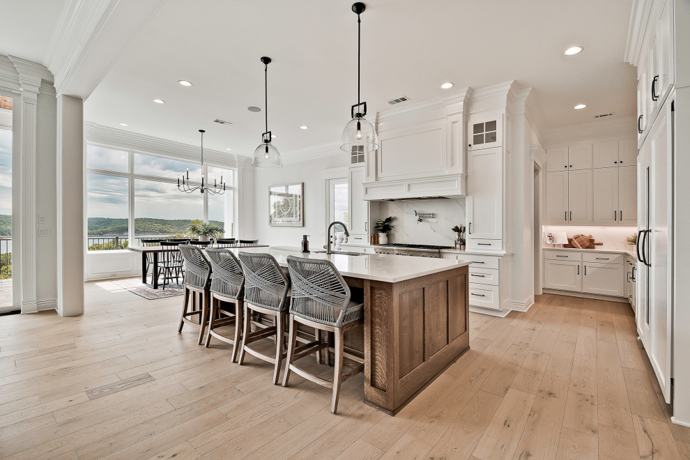 Inspiration for a large craftsman light wood floor kitchen remodel in Other with raised-panel cabinets, white cabinets, quartzite countertops, white backsplash, quartz backsplash, stainless steel appliances, an island and white countertops