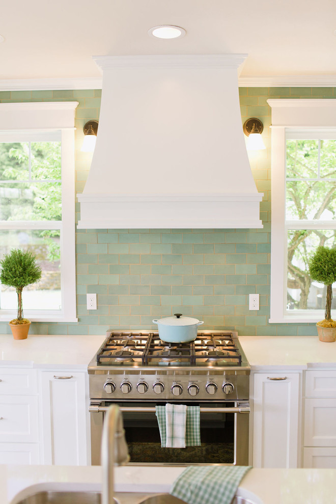 Foto på ett stort medelhavsstil vit kök, med luckor med profilerade fronter, vita skåp, marmorbänkskiva, grönt stänkskydd, stänkskydd i keramik, rostfria vitvaror, mörkt trägolv, en köksö och brunt golv
