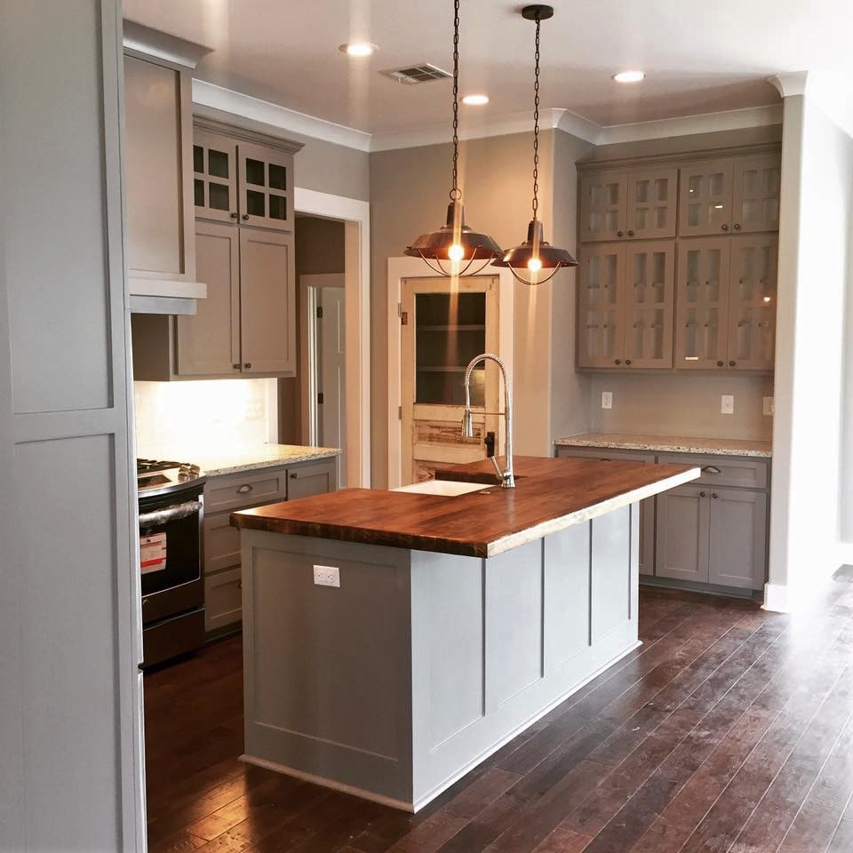 Bild på ett amerikanskt l-kök, med en rustik diskho, luckor med infälld panel, grå skåp, granitbänkskiva, vitt stänkskydd, stänkskydd i tunnelbanekakel, rostfria vitvaror, mörkt trägolv och en köksö